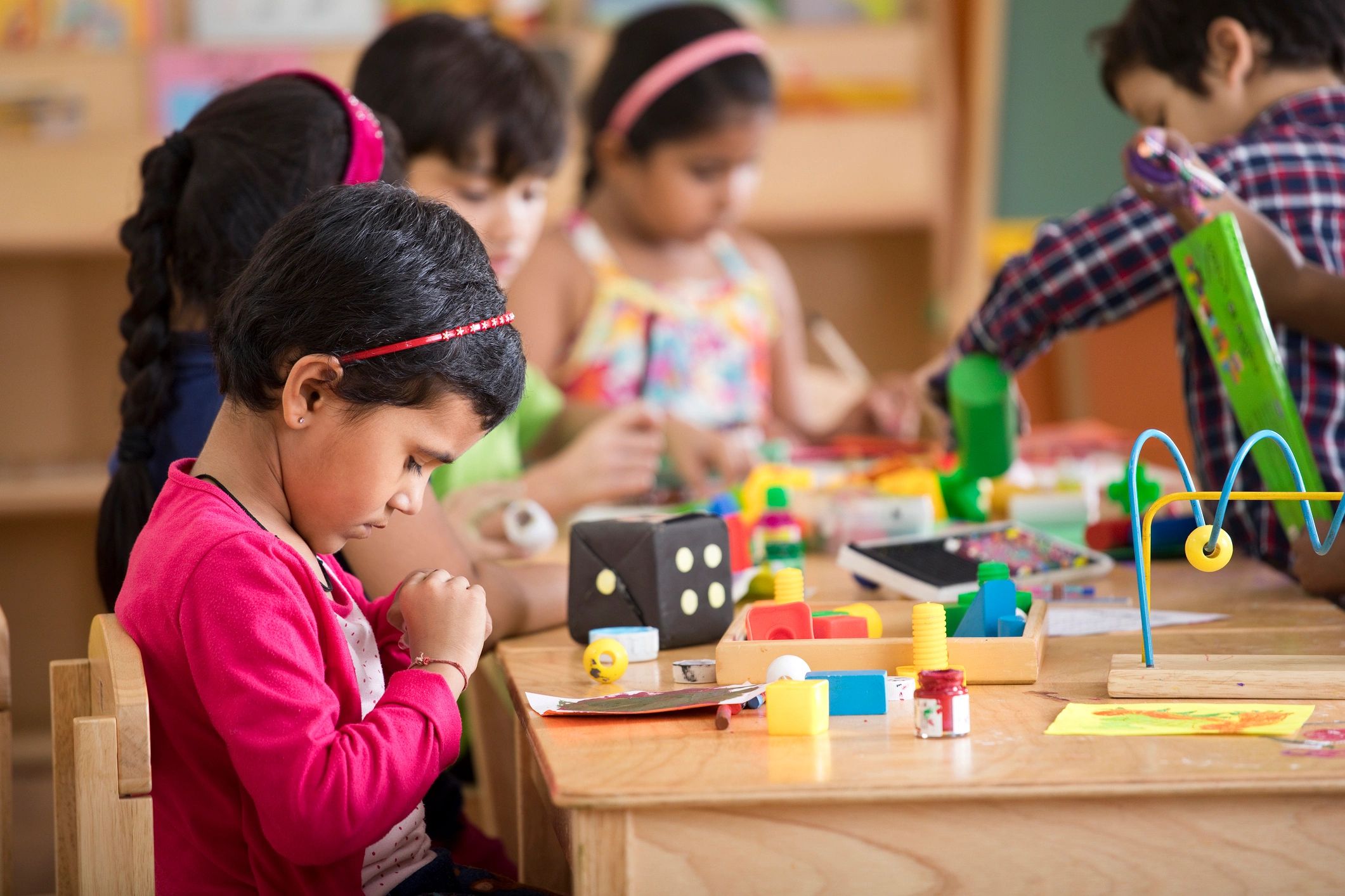 Children painting and drawing together in a bright preschool classroom