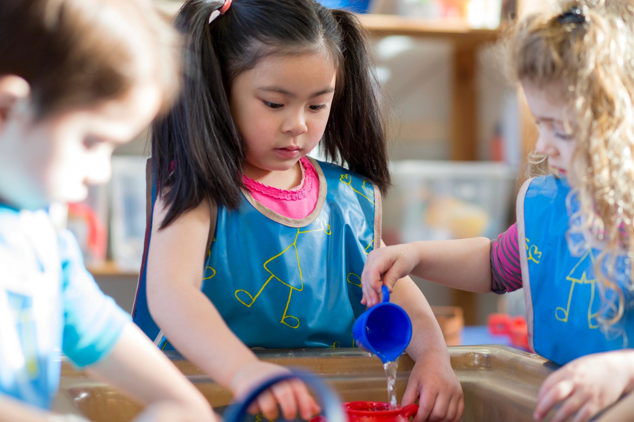 Children playing together at a water table in nursery